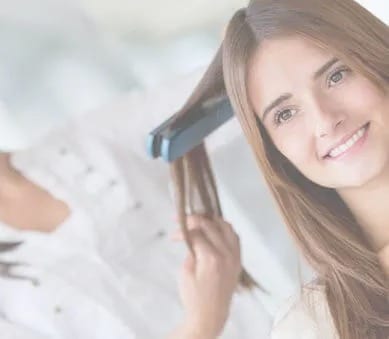 A woman with a long lock of hair being ironed